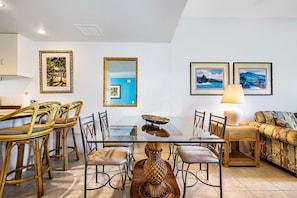 Un coin repas avec une table en verre, des chaises en osier et un canapé.