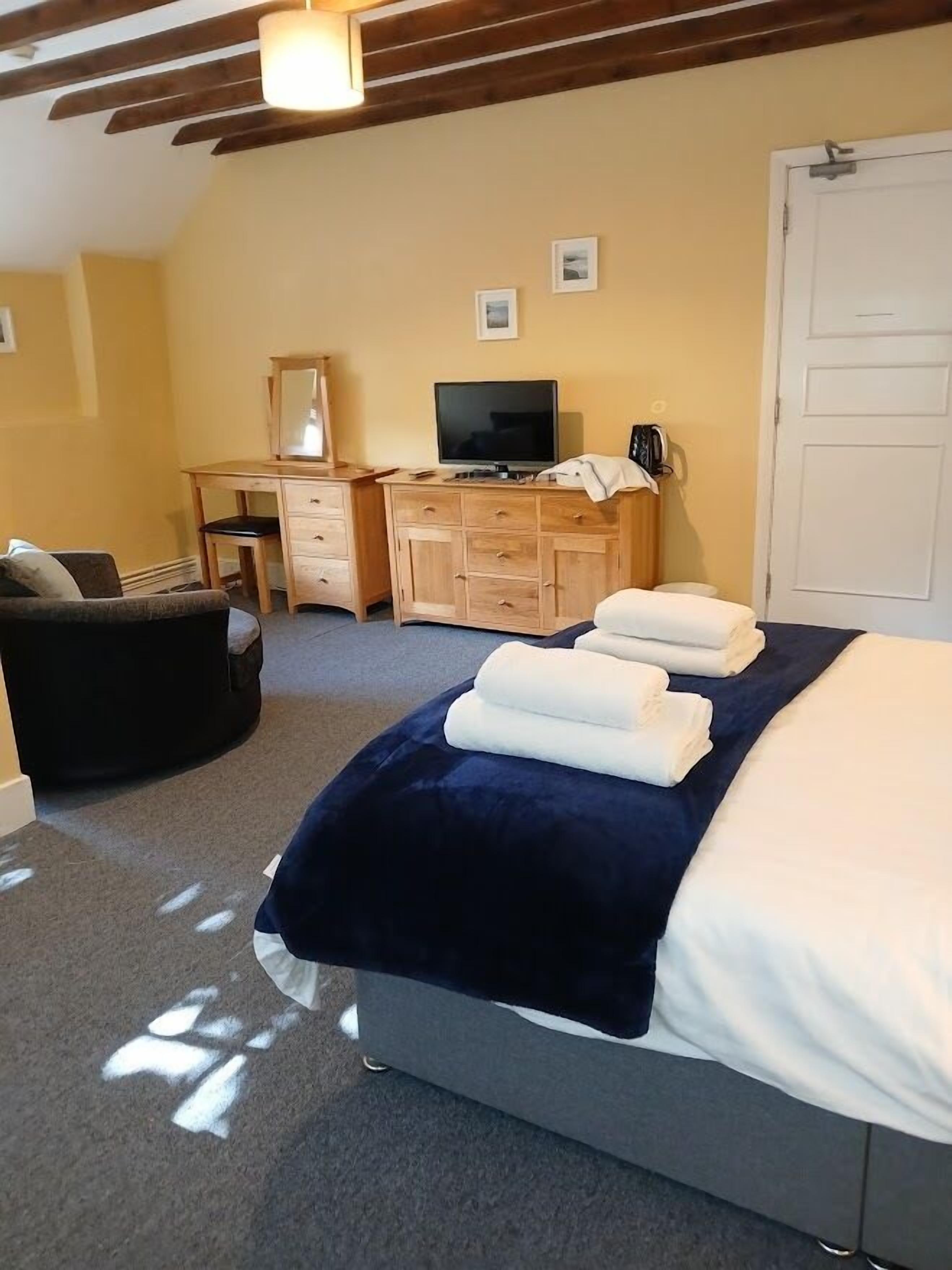 Un dormitorio con cama, escritorio, silla, televisor y armario.