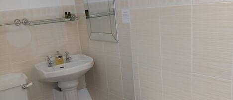 A bathroom with a toilet, pedestal sink, and bathtub.