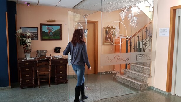 A woman walking towards a glass door with a sign reading "Don Pelayo Hotel". - Hotel Don Pelayo (L'Arboc)