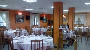 A restaurant with round tables set with white tablecloths, chairs, and wine glasses. - Hotel Don Pelayo (L'Arboc)