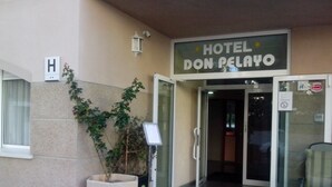 The entrance to Hotel Don Pelayo with a glass door, a sign above the door, and a potted plant beside the entrance. - Hotel Don Pelayo (L'Arboc)