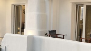 A balcony with a white railing, a chair, and a door leading to an interior space.