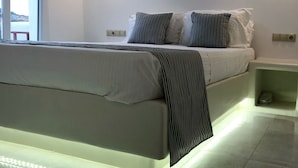 A modern bedroom with a large bed, striped pillows, a bedside table, and a nightstand.