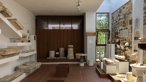 A spacious room with a tiled floor, stone sculptures, and a wooden bench.