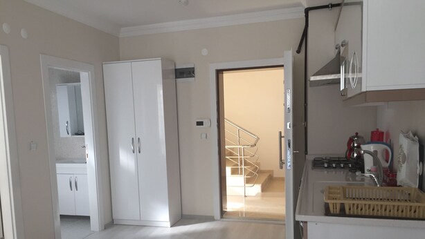A spacious kitchen with modern appliances, a wooden dining table, and a view of the living area. - Dr.Aslan Apart Hotel - Airport (Cubuk)