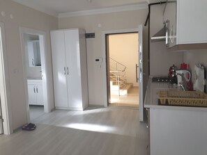 Een ruime keuken met moderne apparatuur, een houten eettafel en uitzicht op de woonkamer.