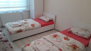 A bedroom with two beds, each with floral bedding and red accents. - Dr.Aslan Apart Hotel - Airport (Cubuk)