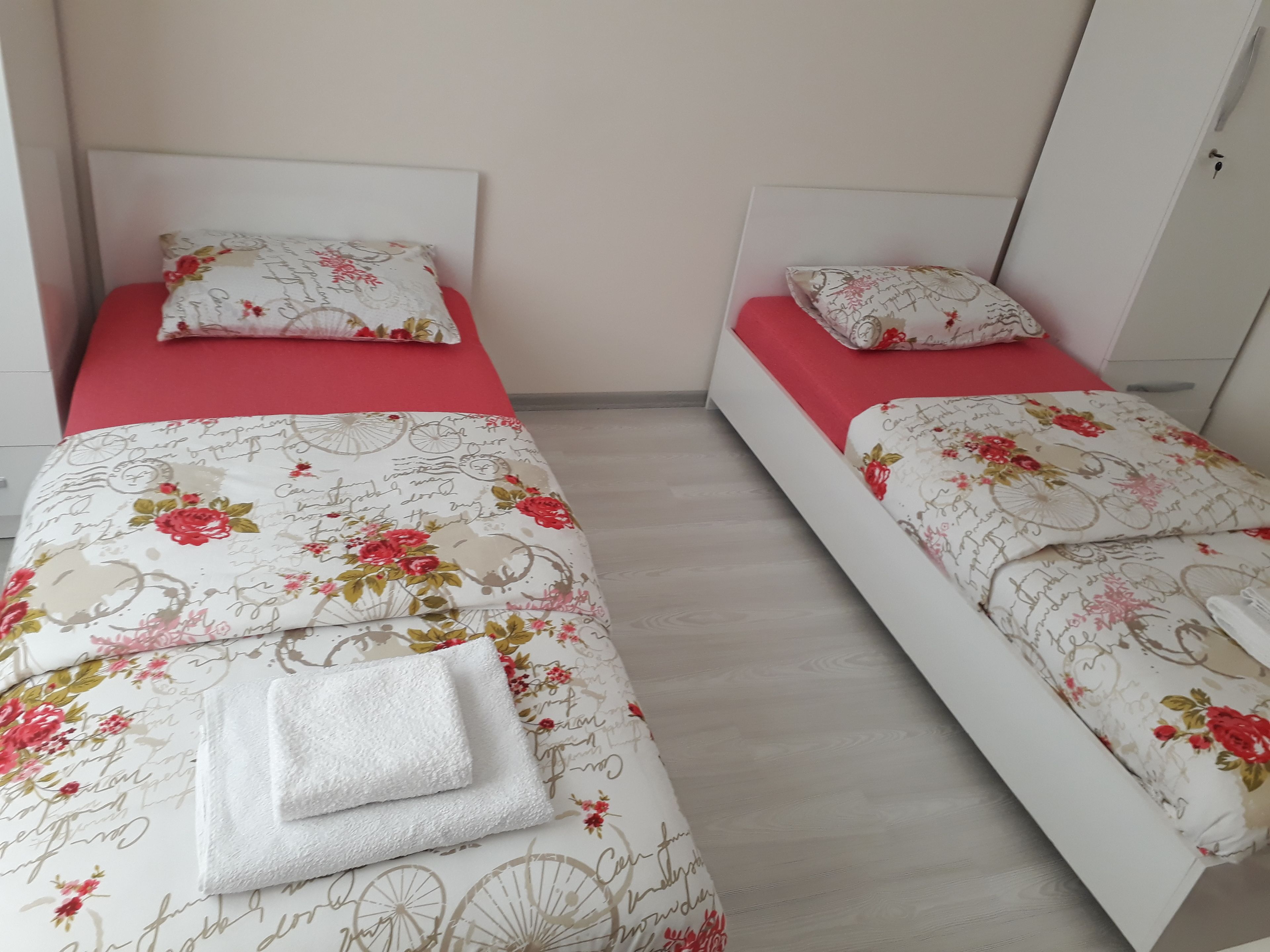 A twin room with two beds, each with floral-patterned bedding and matching pillows.