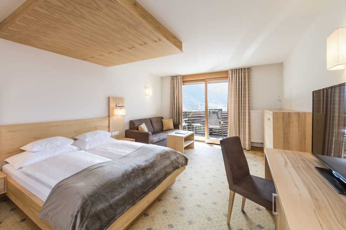 Une chambre d’hôtel avec un grand lit, un canapé, un bureau et une télévision.