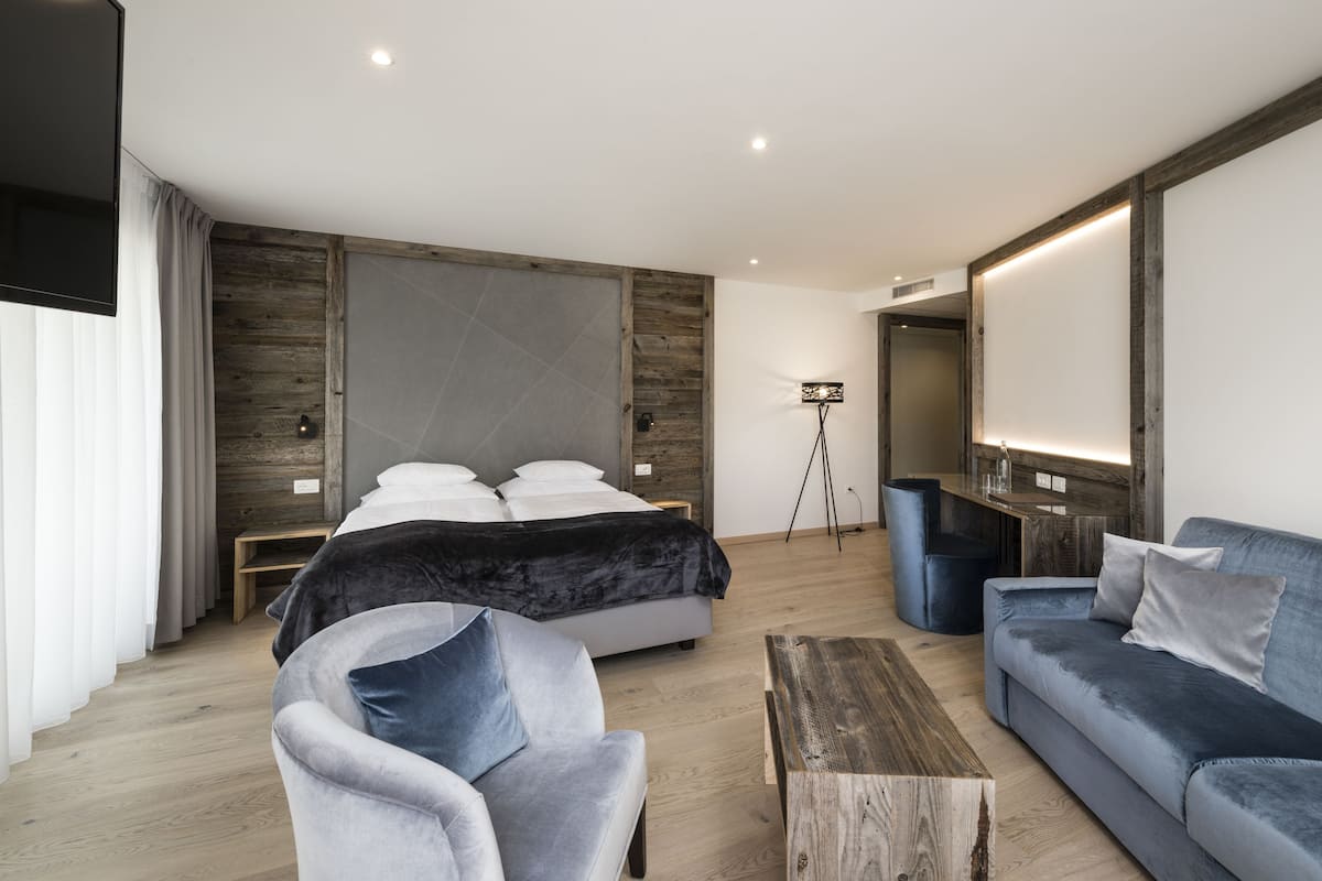 Une chambre moderne avec un grand lit, un canapé, une table basse et une lampe sur pied.