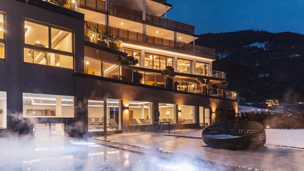 A modern hotel with multiple balconies, a heated outdoor pool, and a mountainous backdrop. - Tuberis Nature & Spa Resort (Tubre)