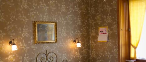 A neatly made bed with a headboard, two wall-mounted lamps, and a chandelier.