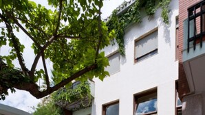 Een modern gebouw met een binnentuin, met een balkon, plantenbakken en een pad.