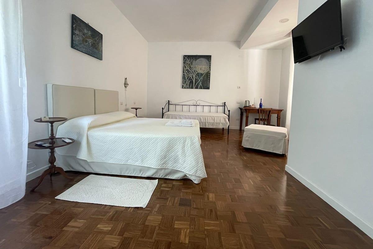 Un dormitorio con dos camas, un escritorio, una silla, un televisor y obras de arte en las paredes.