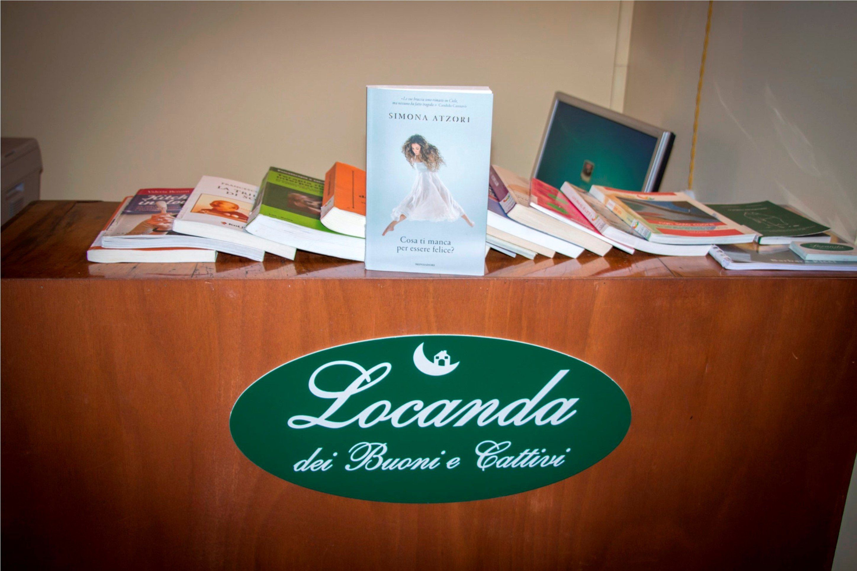 Een houten tafel met een groen, ovaal bord waarop staat: "Locanda dei Buoni e Cattivi".