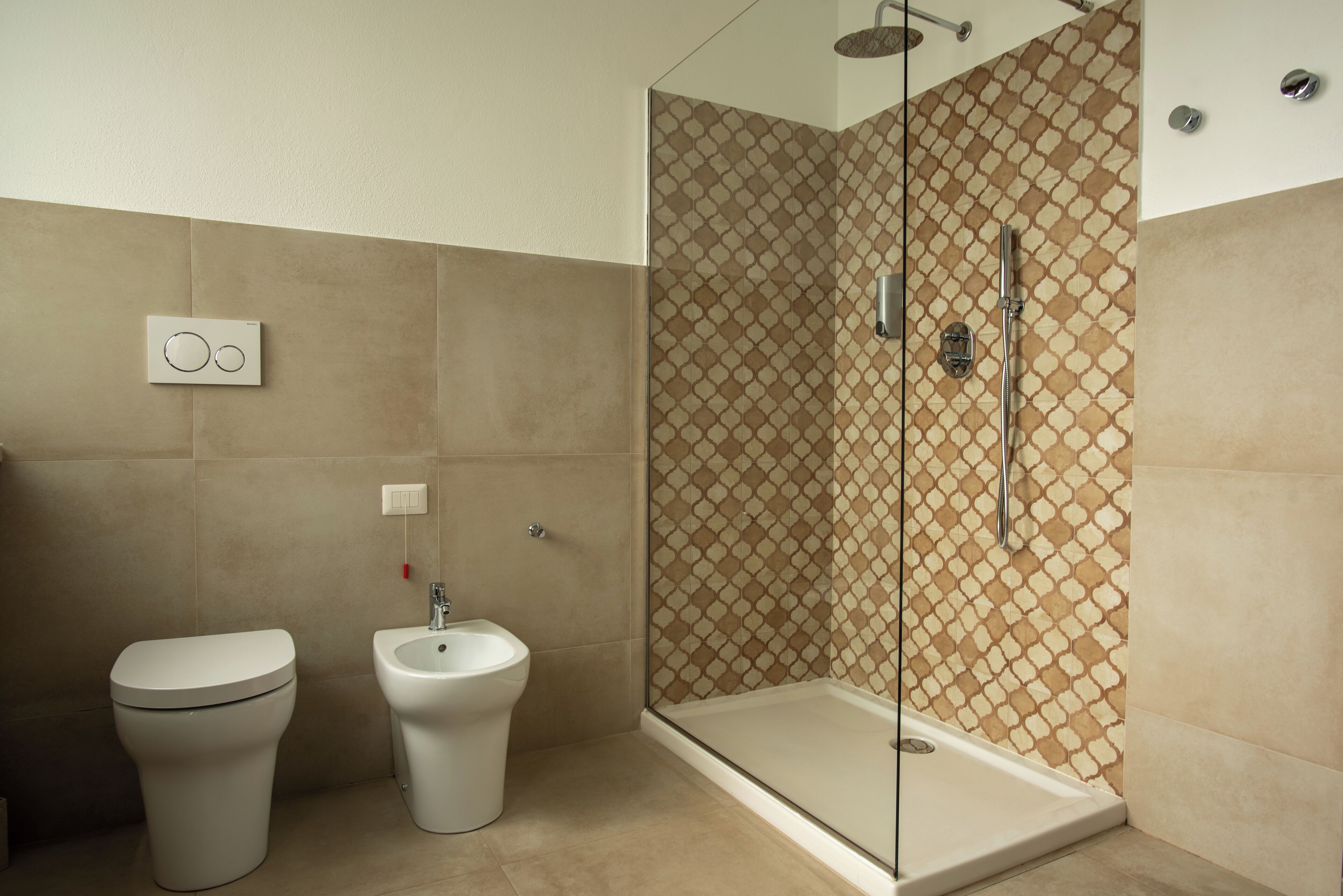 A modern bathroom with a toilet, bidet, and a glass-enclosed shower area.