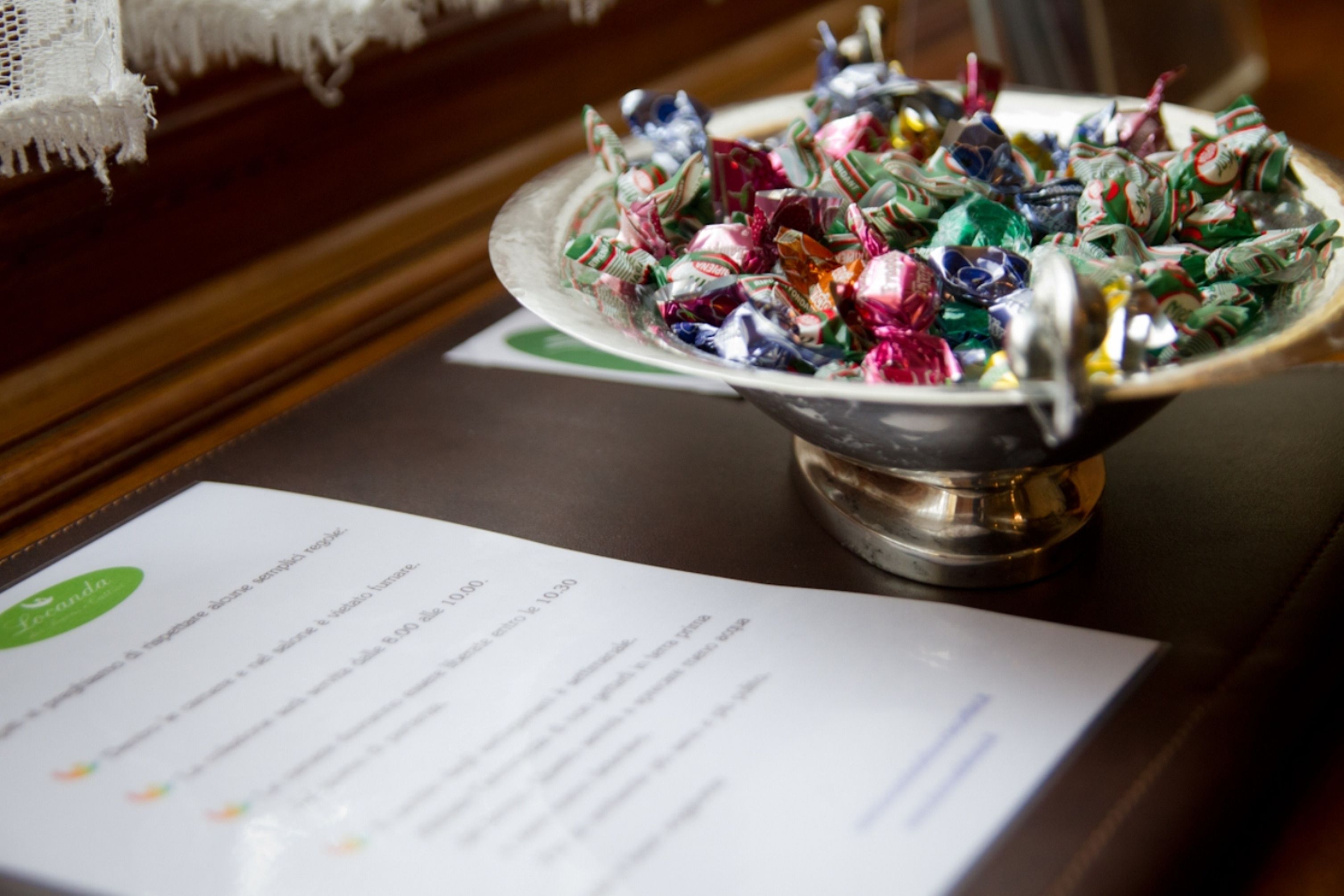 A bowl of assorted candies on a table with a menu in front.