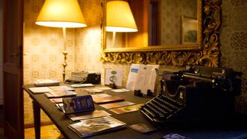 A room with a desk, a typewriter, and two lamps.