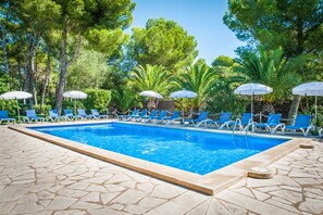 Una piscina al aire libre, sombrillas, sillones reclinables de piscina