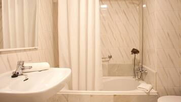 A bathroom with a sink, mirror, shower, and bathtub.