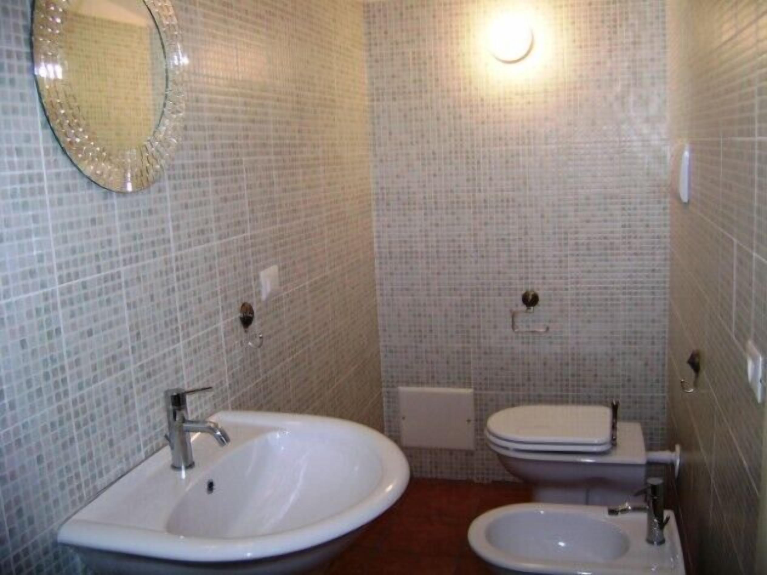 A bathroom with a sink, toilet, and bidet.