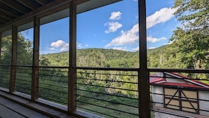 Ein überdachter Außenbereich mit Blick auf einen bewaldeten Hang.