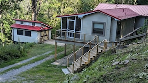 Eine Hütte mit rotem Dach, einer überdachten Veranda und einer Treppe, die zu einer Terrasse führt.