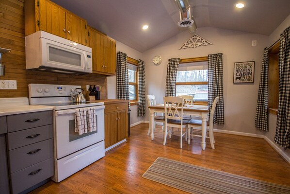 A kitchen with wooden cabinets, a microwave, an oven, and a dining table with chairs.
