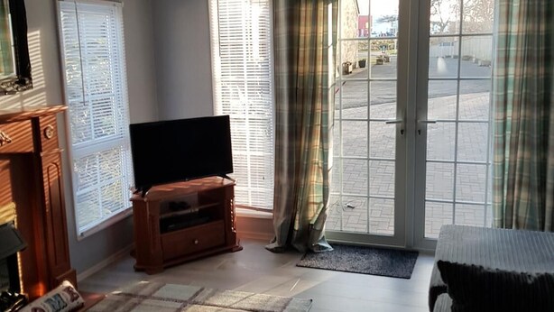 A living room with a television, a fireplace, and a door leading outside. - Tarrareoch Farm (Bathgate)