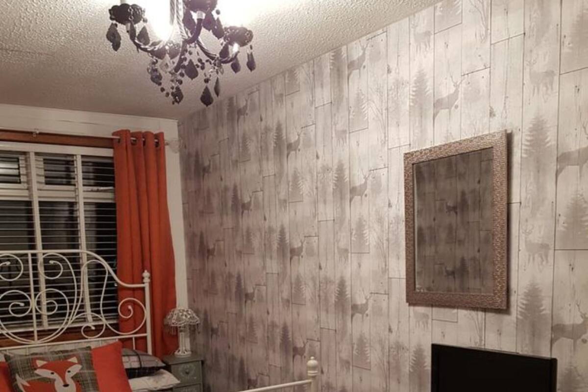 Quarto com cama, televisão, cômoda e janela com cortinas.