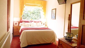 A bedroom with a bed, bedside table, lamp, window with curtains, and a mirror. - Tarrareoch Farm (Bathgate)
