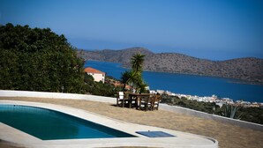 Piscina com vista para uma cidade costeira e montanhas.