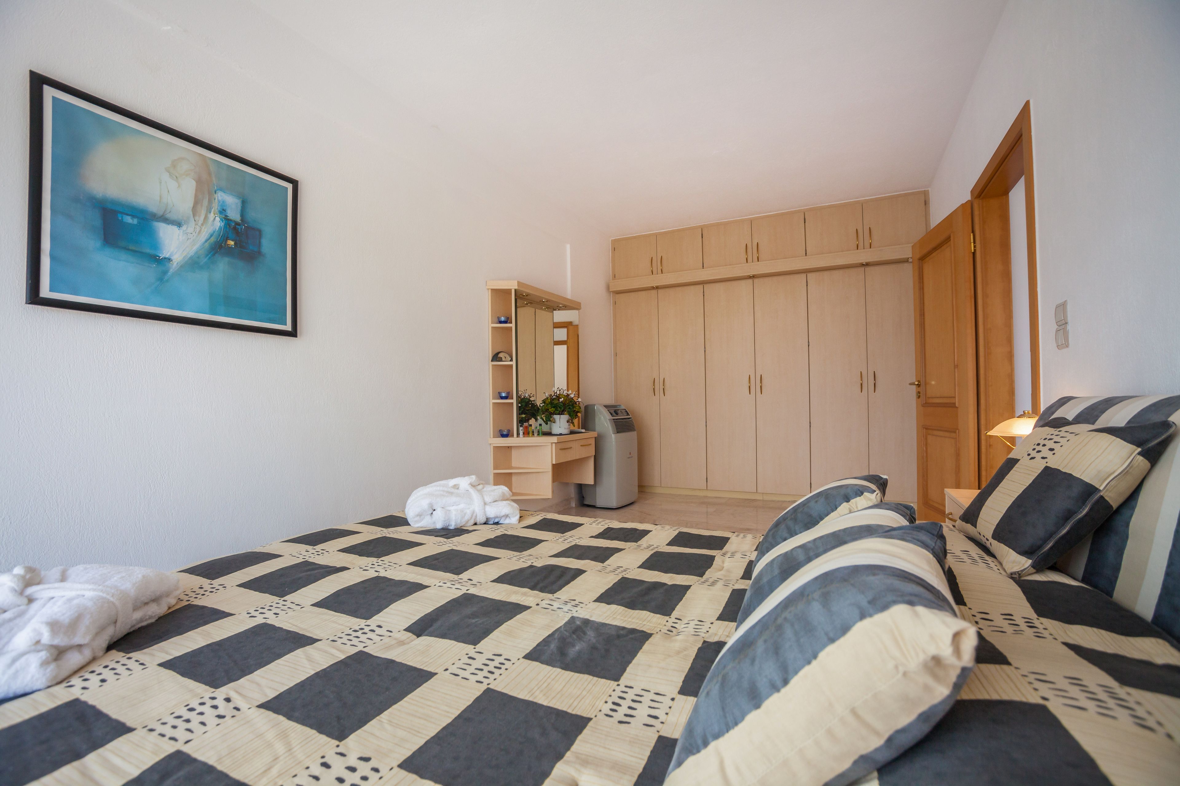 Une chambre à coucher avec un lit, une armoire, un bureau et un tableau accroché au mur.