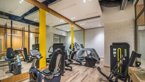 Un gimnasio con equipamiento de ejercicio, espejos y suelo de madera.