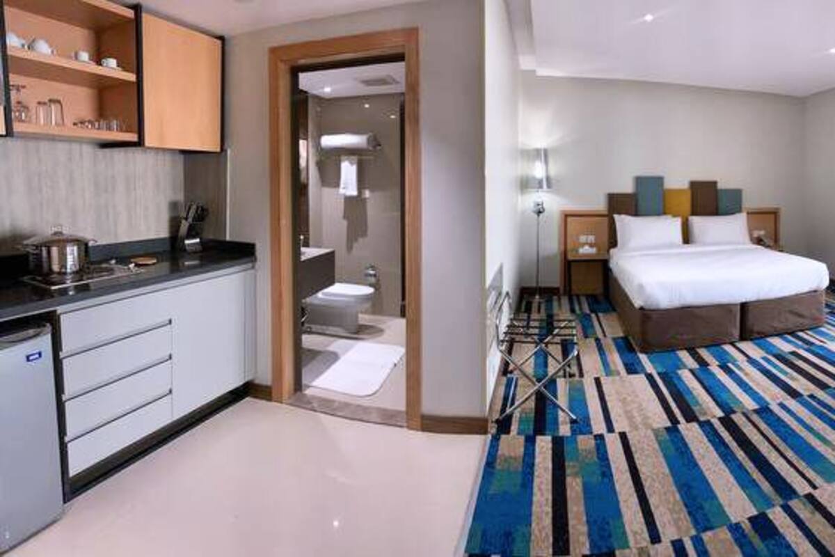 A hotel room with a bed, a desk, a chair, a TV, and a bathroom.