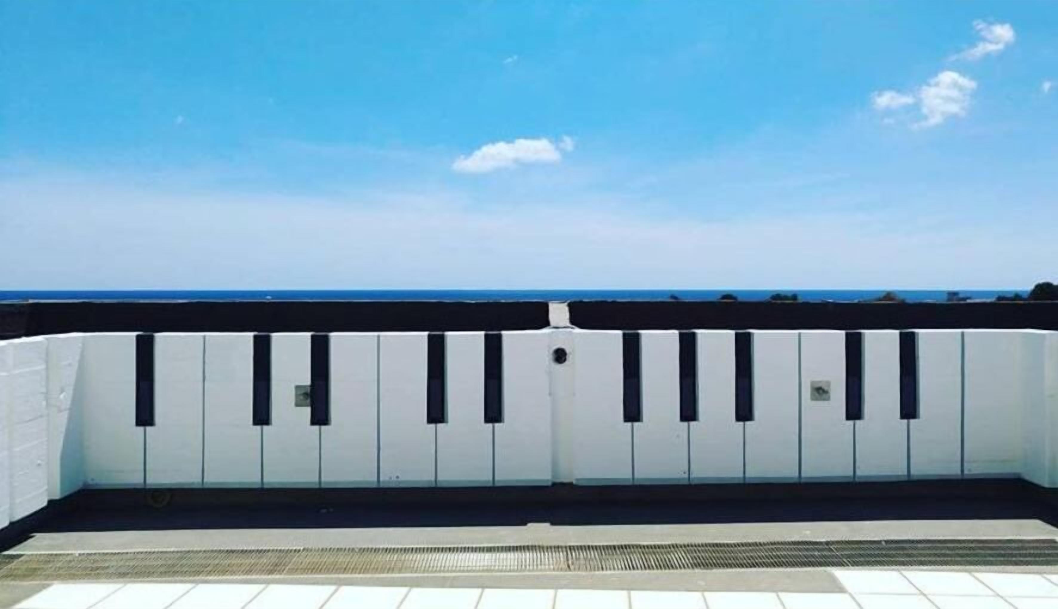 Un balcon blanc avec une balustrade en métal donnant sur une plage.