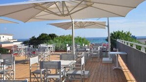 A rooftop terrace with outdoor seating and umbrellas, overlooking a coastal area. - Hotel Intervallo (Porto Cesareo)