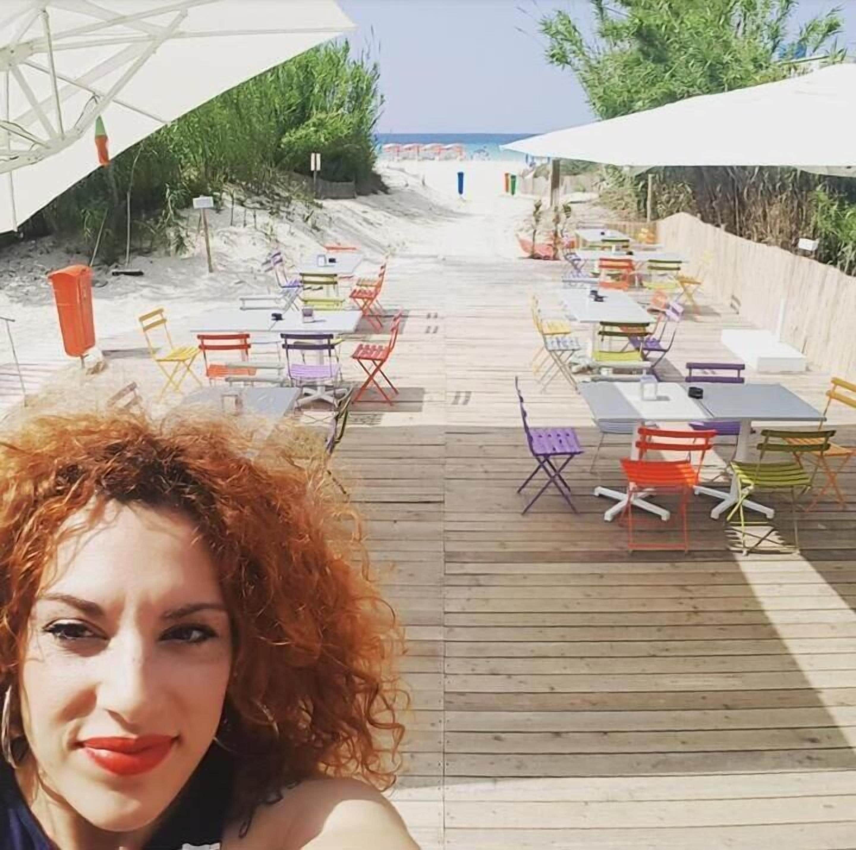 Een restaurant aan het strand met terras, inclusief tafels en stoelen, en uitzicht op zee.
