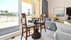 A room with a balcony, a sofa, two chairs, a table, and a TV. - Large lobby-level end condo w/patio access to beach & pool! (Destin)