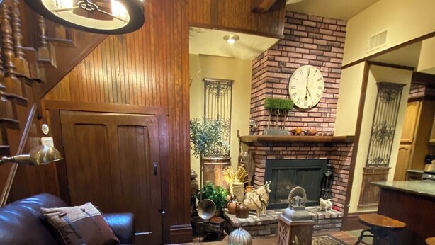A cozy living room with a fireplace, leather sofa, and a wooden staircase. - HISTORIC VERY ROMANTIC 1883 SAN FRANCISCO CARRIAGE HOUSE (San Francisco)