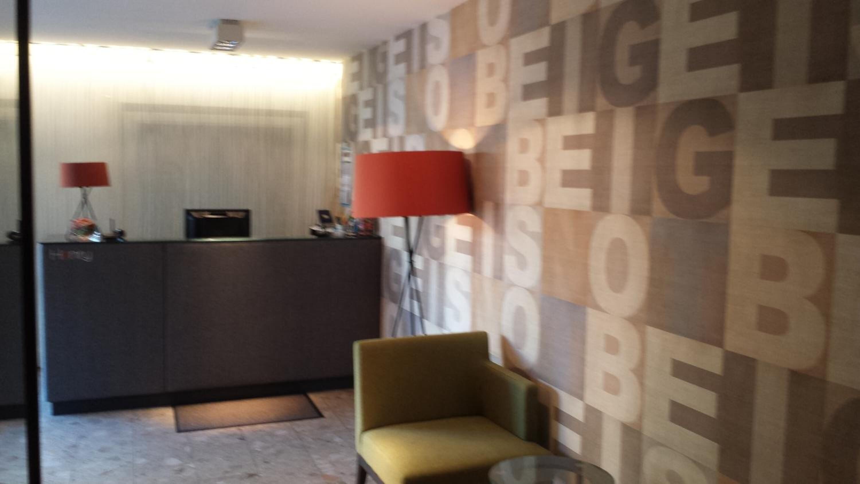 A reception area with a desk, a red lamp, and a patterned wall.
