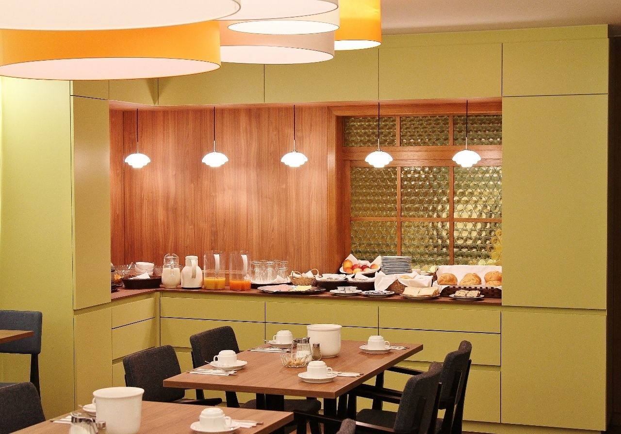 A dining area with green walls, wooden paneling, and a breakfast buffet.