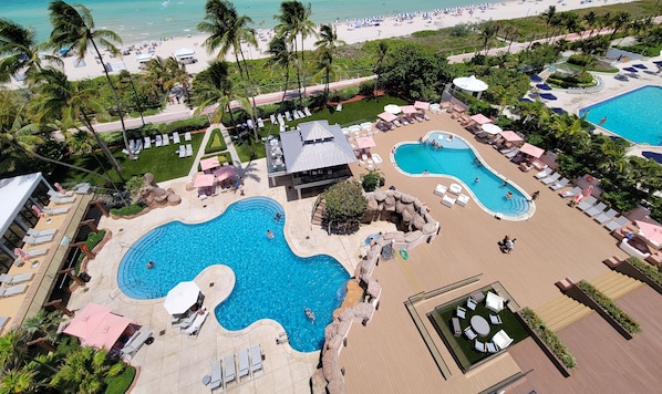A resort with multiple swimming pools, lounge areas, and a beach.