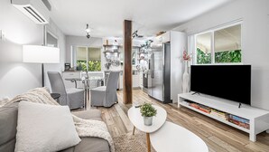 Moderni olohuone, jossa on sohva, sohvapöytä ja TV-taso.