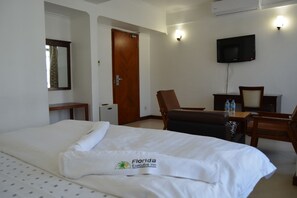A hotel room with a bed, a desk, a chair, a television, and a door. - Florida Executive Inn (Dar es Salaam)