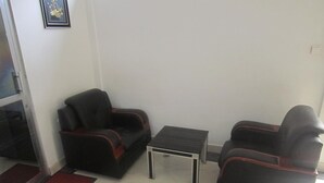 A small living area with two black sofas, a small table, and a red doormat. - Florida Executive Inn (Dar es Salaam)