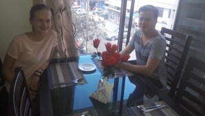 Two people seated at a table with a vase of red roses, a plate, and a spoon. - Florida Executive Inn (Dar es Salaam)