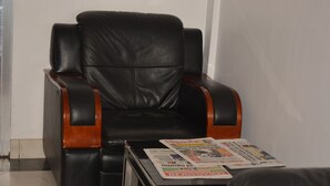 A black leather armchair with wooden armrests and a small table with newspapers. - Florida Executive Inn (Dar es Salaam)