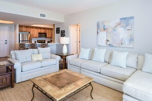 A living room with two sofas, a coffee table, and a kitchen in the background.